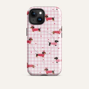 Könnte beinhalten: Handyhülle mit einem rosa-weiß karierten Vichy-Muster und sich wiederholenden Illustrationen von Dackeln in roten Pullovern mit weißen Punkten. Kleine rote Herzen sind über das Design verstreut.