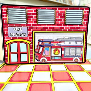 Op de afbeelding: Een kleurrijke brandweerkazerne speelset met een rode bakstenen gevel, ramen en een garagedeur. Het bord leest "FIRE STATION". Binnen in de garage staat een rode brandweerwagen. De basis heeft een rood-wit geblokt patroon.
