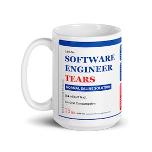 Puede incluir: Taza de cerámica blanca con el texto "SOFTWARE ENGINEER TEARS" en azul y rojo. La taza también incluye texto sobre solución salina normal y una capacidad de 444 ml.