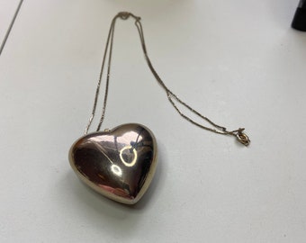 Long gold tone chain with a large gold tone puffy heart pendant. Chain is 15 inches long. Pendant is 2 inches long by 2 inches wide.