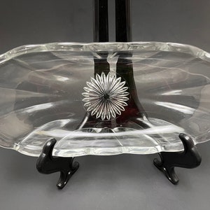 Puede incluir: Un plato de servir de vidrio transparente con un borde festoneado y un diseño decorativo en forma de estrella en el centro.