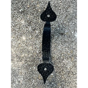 May include: Black metal door handle with a decorative, hammered finish and a pointed, heart-shaped design at the top and bottom.