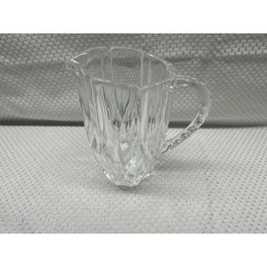 May include: A clear glass jug with a faceted design and a beaded handle.