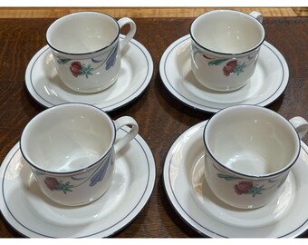 May include: Set of four white teacups and saucers with a floral design. The cups and saucers have a blue and green trim.