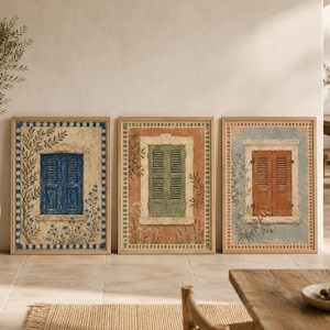 May include: A set of three framed wall art prints featuring illustrations of windows with shutters. The first shows blue shutters on a cream background, the second green shutters on a terracotta background, and the third red shutters on a blue background.
