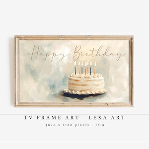 May include: A framed art print featuring a birthday cake with lit candles. The words "Happy Birthday" are written in elegant script above the cake. The artwork has a soft, watercolor-like background in shades of blue and white.