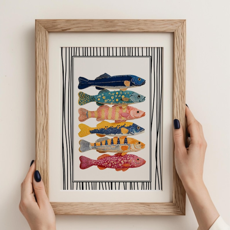May include: A framed art print displaying six vibrantly coloured fish illustrations. The fish are in various colours and patterns, including blue, green, yellow, and red. The artwork is set against a white background with a black and white striped border, framed in light wood.