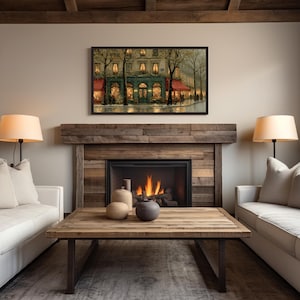 Pode incluir: Uma pintura emoldurada de uma cena de rua europeia est&aacute; pendurada acima de uma lareira. A pintura retrata um edif&iacute;cio com toldos vermelhos e uma fachada turquesa. Uma mesa de centro de madeira com vasos decorativos fica em frente a um sof&aacute; branco e uma lareira acesa.