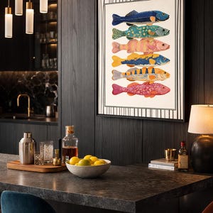 May include: A framed print displaying six vibrantly coloured fish illustrations. The fish are in shades of blue, green, pink, yellow, and orange. The artwork is set in a contemporary kitchen with dark wood panelling.