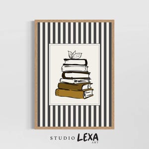 May include: A framed art print featuring a stack of books with a leaf accent. The artwork is a sketch-style illustration in black and brown tones, set against a white background. The frame has a striped pattern.