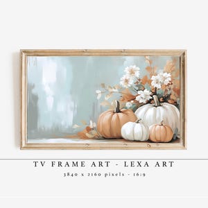 May include: A framed artwork featuring a still life of pumpkins and flowers. The pumpkins are in shades of orange and white, with a backdrop of soft blue and brown hues. The artwork is labeled "TV FRAME ART - LEXA ART".