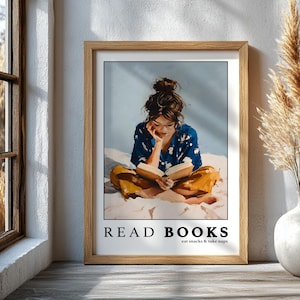 Könnte beinhalten: Gerahmter Kunstdruck mit einer Person, die ein Buch liest. Die Person trägt ein blaues Oberteil mit Blumenmuster und eine gelbe Hose. Der Druck hat den Text "READ BOOKS eat snacks & take naps" in schwarzer Schrift.