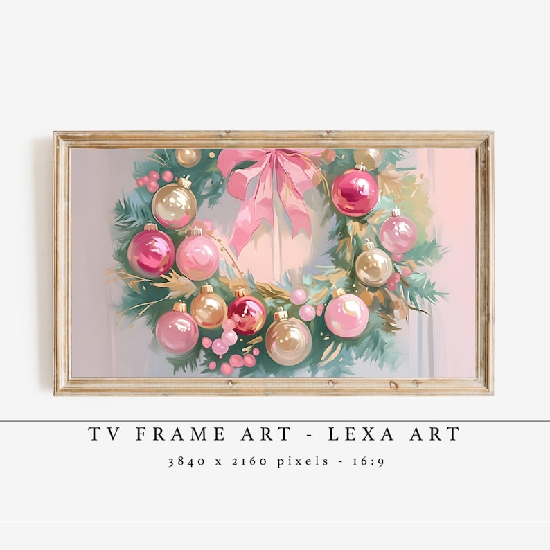 Op de afbeelding: Een ingelijste digitale kunstprint met een kerstkrans met roze en gouden ballen, een roze strik en groene bladeren. De tekst "TV FRAME ART - LEXA ART" wordt onder de afbeelding weergegeven.