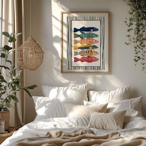 May include: A framed art print displaying six vibrant fish illustrations. The fish are in various colours and patterns, including blue, green, orange, yellow, and red. The artwork is set against a white background with a black and white striped border.