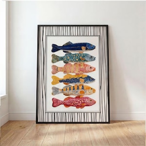 May include: A framed art print featuring six colorful fish illustrations. The fish are arranged vertically, each with unique patterns and hues of blue, yellow, orange, and red. The frame has a black and white striped border, adding a decorative touch.
