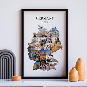 May include: A framed print featuring a collage of photographs arranged in the shape of Germany. The word "GERMANY" and the year "2025" are printed at the top. The frame is black, and the print is displayed on a white surface.