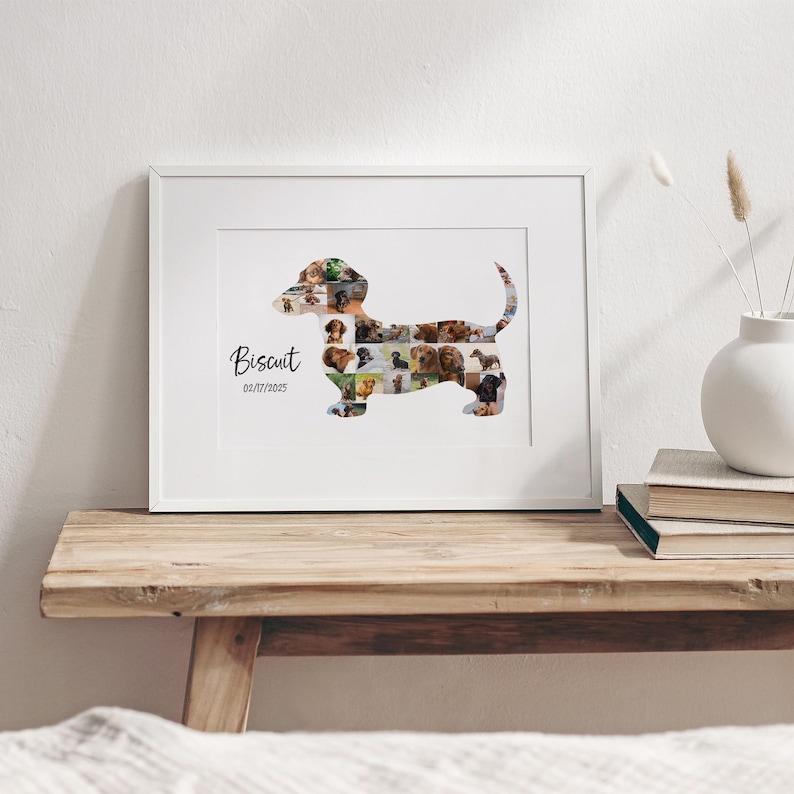 May include: A framed photo collage in the shape of a dachshund, filled with various dog photographs. The name "Biscuit" and the date 01/17/2015 are written in black script. The frame is white, resting on a wooden surface.