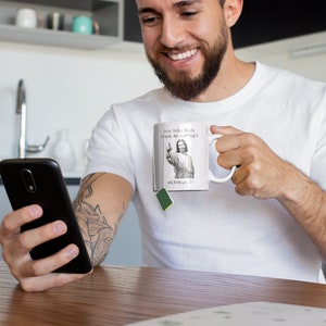 K&ouml;nnte beinhalten: Eine wei&szlig;e Keramiktasse mit einem Schwarzwei&szlig;bild von Jesus, der einen Finger hochh&auml;lt, und dem Text "Wie macht Jesus seinen Kaffee? Hebr&auml;er 13:17".