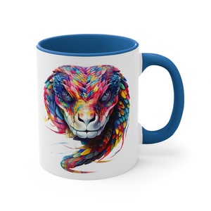May include: A white ceramic coffee mug with a blue rim and handle. The mug features a colourful illustration of a snake's head and part of its body.