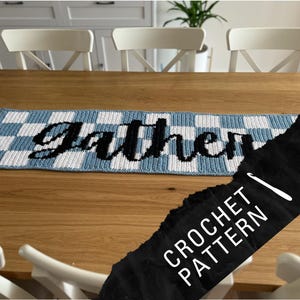 May include: A blue and white checkered crochet table runner with the word "Gather" in black cursive. The image also includes a black banner with the words "CROCHET PATTERN" in white.