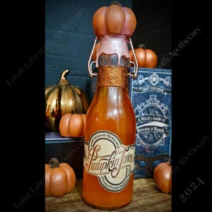May include: A glass bottle with a pumpkin-shaped stopper filled with orange liquid. The bottle has a label that reads "Pumpkin Juice" with the words "The True Fresh-Made Flavor" underneath. The bottle is surrounded by small pumpkins.