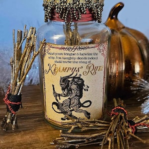 May include: A glass bottle with a red and gold label that reads "Mind your tongue & beware the whip, for naughty deeds indeed shall invite the sting of Krampus Rute". The bottle is decorated with a gold tassel and a red cork. The bottle is sitting on a wooden surface with a bundle of twigs tied with red string.