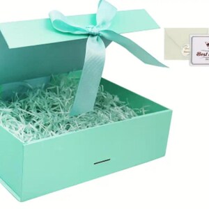 May include: An open, mint-green gift box with a matching ribbon tied in a bow. The box is filled with shredded paper and includes a small card that reads "Best wishes to you."