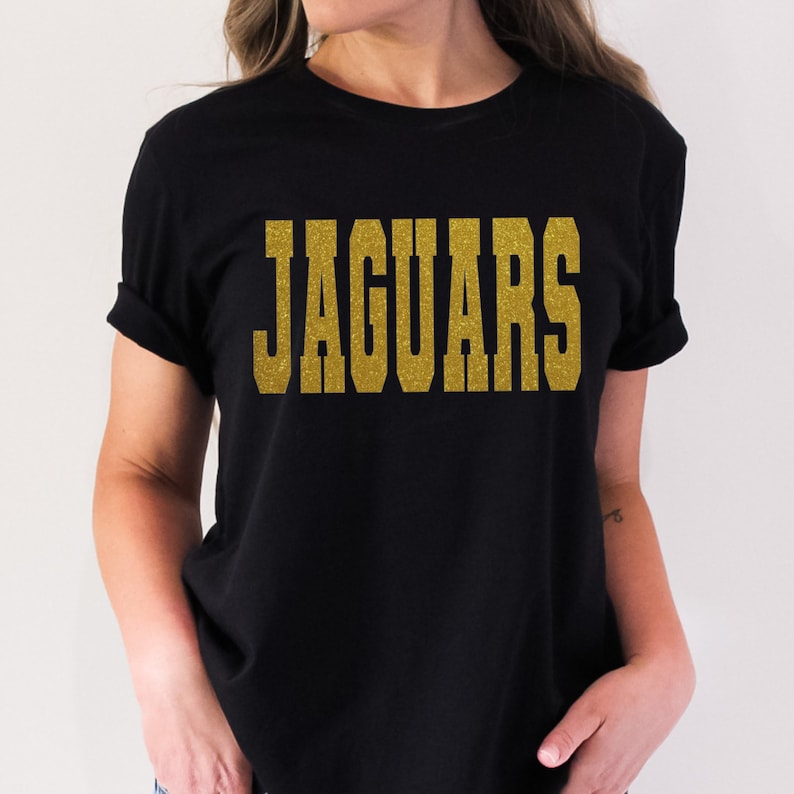 K&ouml;nnte beinhalten: Schwarzes T-Shirt mit dem Wort "JAGUARS" in goldenen Glitzerbuchstaben.