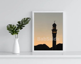 Op de afbeelding: Een ingelijste print van een silhouet van een minaret tegen een zonsondergang. De minaret heeft een halve maan bovenop en is verlicht met ramen. De tekst "Bab Saida" is zichtbaar in het midden onderaan de print.