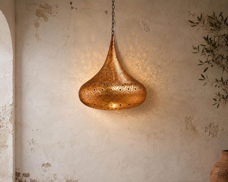 May include: A teardrop-shaped pendant light fixture crafted from metallic gold-toned material. The surface features intricate, laser-cut geometric patterns that allow light to project outward, creating a detailed shadow effect on the wall.