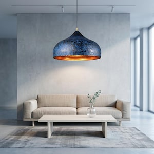 May include: A modern, blue pendant light with a textured surface hangs above a beige sofa and light wood coffee table. The interior of the light fixture is gold, and the room has a minimalist design with a neutral color palette.