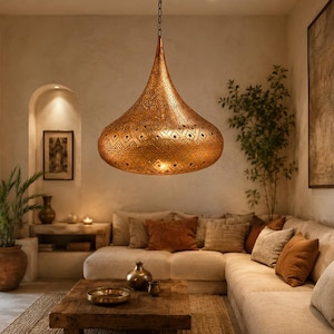 May include: A large, teardrop-shaped pendant light fixture crafted from metallic copper-toned material. The surface features an intricate, laser-cut geometric pattern that allows light to pass through, suspended from the ceiling by a thin metal chain.