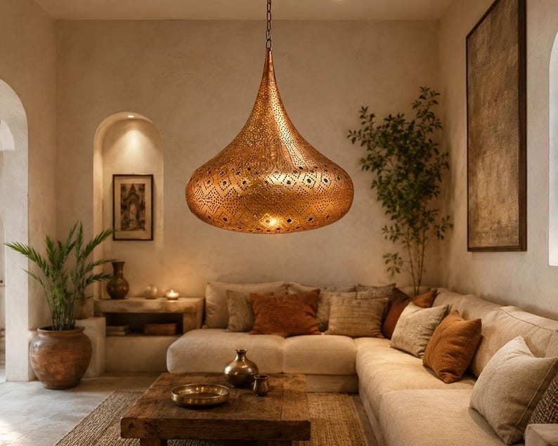May include: A large, teardrop-shaped pendant light fixture crafted from metallic copper-toned material. The surface features an intricate, laser-cut geometric pattern that allows light to pass through, suspended from the ceiling by a thin metal chain.