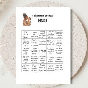 以下が含まれることがあります： 上部に「BLACK MAMA SAYINGS BINGO」と書かれた白いビンゴカード。カードには、母親と子供の水彩イラストが描かれています。ビンゴの正方形には、「Fix your face」や「I brought you into this world」などのフレーズが含まれています。