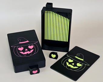 May include: A black rectangular diamond painting tray set featuring a pumpkin with heart-shaped eyes and a witch hat. The set includes a tray with a lime green grooved interior, a lid with a neon green pumpkin design, and a matching black storage box.