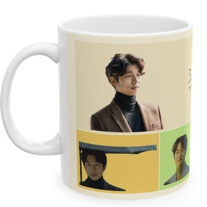 May include: White ceramic mug with a collage of images of a man with dark hair. The images are in a grid pattern with a yellow, green, and beige background. The text "Goblin" is written in Korean on the right side of the mug.