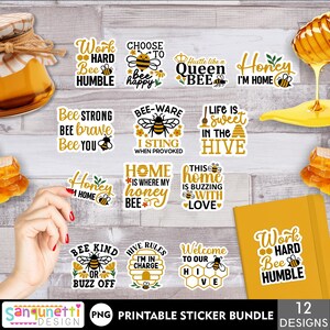 Puede incluir: Un conjunto de 12 pegatinas imprimibles con temática de abejas con diferentes lemas, que incluyen "Trabaja duro, sé humilde", "Elige ser feliz", "Esfuérzate como una reina abeja", "Cariño, estoy en casa", "Sé fuerte, sé valiente, sé tú", "Cuidado, pico cuando me provocan", "La vida es dulce en la colmena", "El hogar es donde está mi miel", "Este hogar zumba de amor", "Sé amable o lárgate", "Reglas de la colmena, estoy a cargo", y "Bienvenido a nuestra colmena".