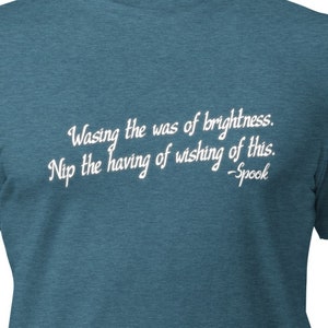 May include: A teal blue t-shirt with a white quote that reads "Wasing the was of brightness. Nip the having of wishing of this. -Spook"