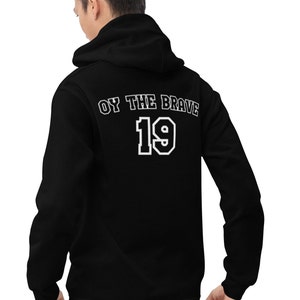 Puede incluir: Sudadera con capucha negra con texto blanco que dice "Oy the Brave 19" en la espalda.