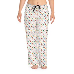 May include: White pajama pants with a repeating pattern of colorful Christmas lights. The lights are red, green, blue, yellow, and orange, connected by a black wire. The pants have a black drawstring.
