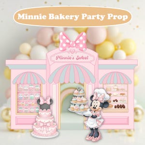 Könnte beinhalten: Eine rosa Minnie Bakery Party-Requisite mit einer Cartoon-Bäckerei-Fassade, die Minnie Mouse mit Cupcakes zeigt. Die Bäckerei hat eine rosa und blaue Markise, Regale mit Süßigkeiten und eine dreistöckige Torte. Der Text "Minnie's Sweet" ist sichtbar.