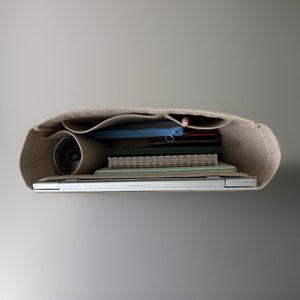 May include: A beige felt tote bag with a laptop, notebooks, a pencil, and a water bottle inside. The laptop has the text "ELITEBOOK" on the bottom.