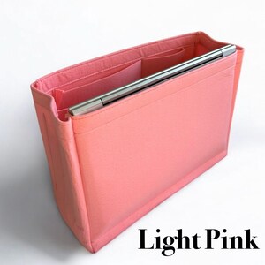 May include: Light pink felt bag organizer with multiple compartments and a laptop sleeve. The organizer is designed to fit inside a larger bag.