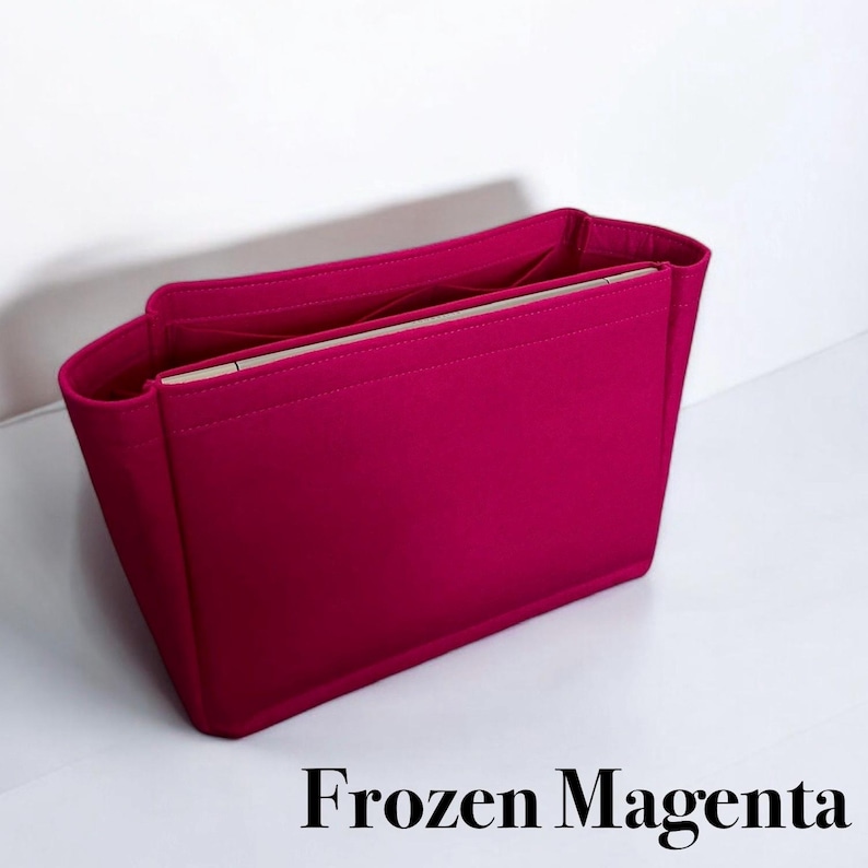 May include: A bright pink felt bag insert with a light pink lining. The insert is designed to fit inside a handbag and help organize the contents.