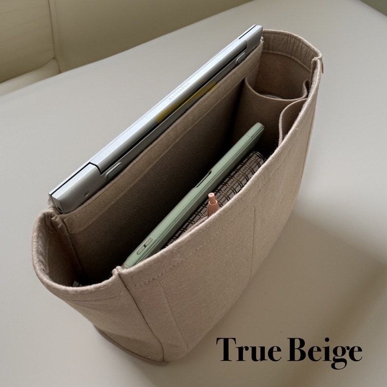 May include: Beige felt bag organizer with multiple compartments. A laptop, tablet, and pen are inside the bag. The text "True Beige" is printed below the bag.