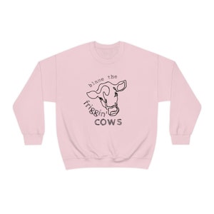May include: Pink sweatshirt with a black line drawing of a cow's head and the text "blame the frigg'n COWS"
