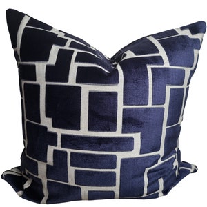 May include: A navy blue throw pillow with a white geometric pattern. The pillow is made of a soft, plush fabric and has a square shape.