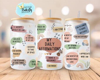 Op de afbeelding: Drie witte bekers met bamboe deksels en rietjes. Elke beker heeft een andere set positieve affirmaties die erop zijn gedrukt. De affirmaties omvatten "Ik ben sterk", "Ik ben mijn dromen waard" en "Ik mag fouten maken".