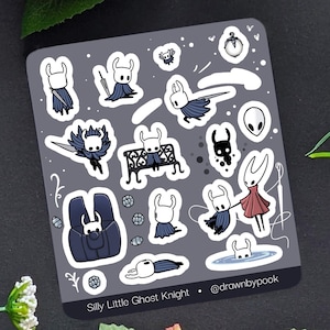 May include: A sheet of stickers featuring cartoon characters from the game Hollow Knight. The stickers are in white, black, and grey, with some characters holding weapons or wearing capes. The text "Silly Little Ghost Knight" is at the bottom.
