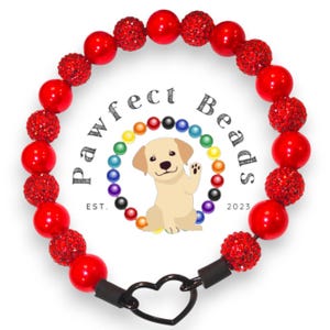 Pode incluir: Coleira de cão de contas vermelhas com fecho em forma de coração. As contas são uma mistura de vermelho sólido e vermelho com strass transparente. A coleira tem o texto "Pawfect Beads Est. 2023".